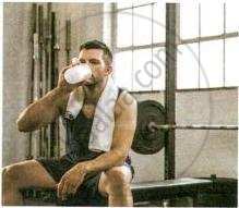 The image displays an educational photograph of an athlete sitting on a gym bench with a towel around his neck while drinking water from a shaker bottle after a workout.