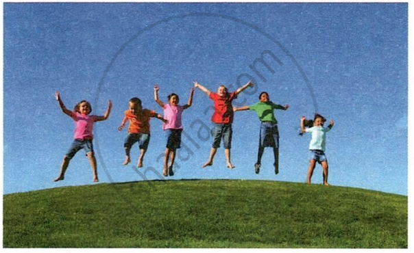 The image displays a photograph of a group of children joyfully jumping together on a grassy hill against a clear blue sky.