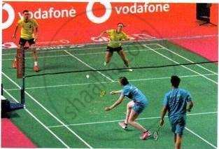The image displays a photograph showing a competitive badminton match in progress with players on the court.