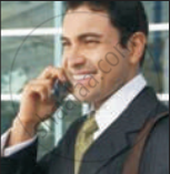 The image shows a smiling businessman in formal attire talking on a mobile phone near a window.