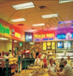 The image shows a busy food court with several restaurants, counters, tables and customers inside a shopping mall.